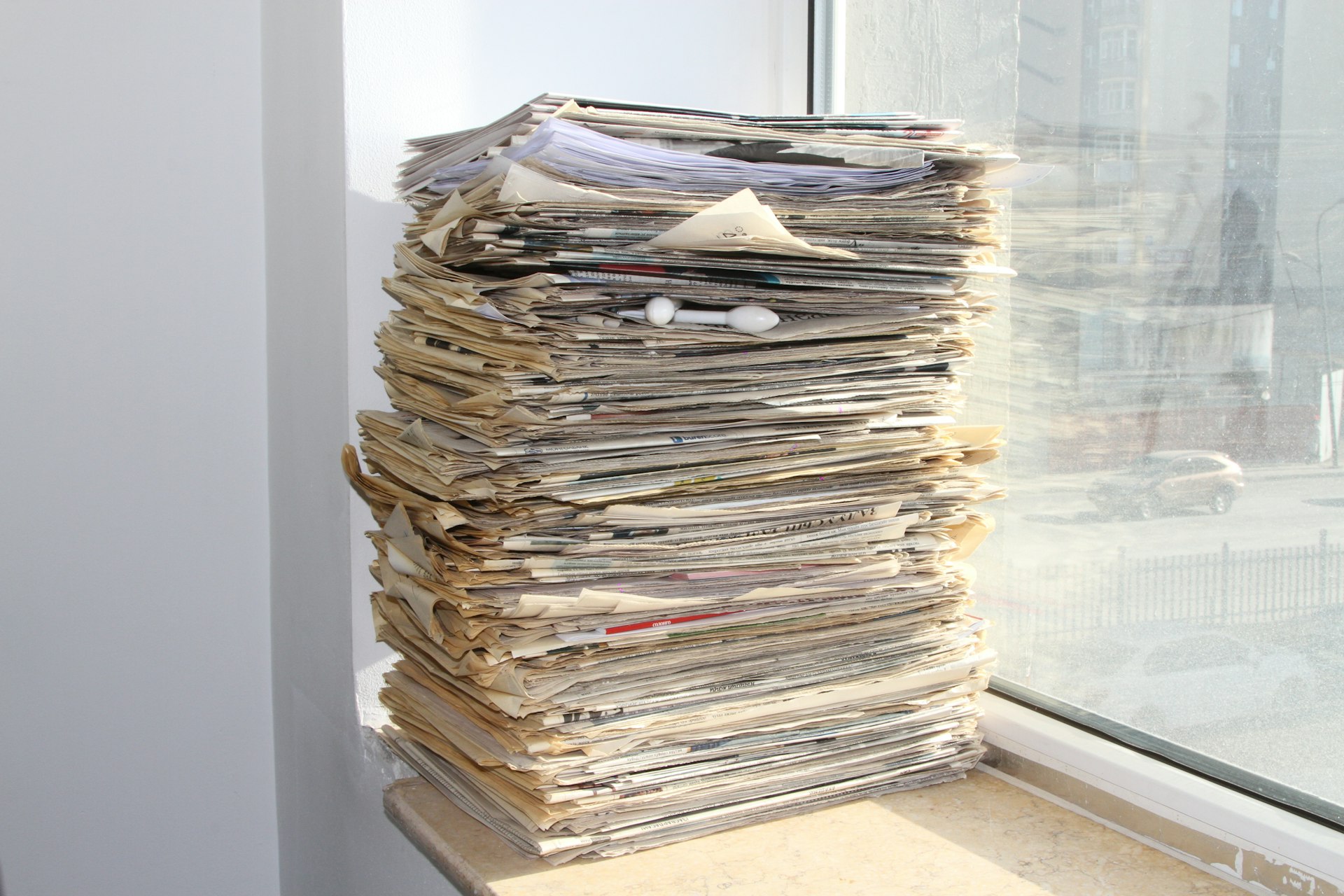 a stack of newspapers sitting on top of a window sill